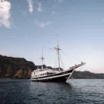 Aliikai Voyage phinisi at anchor beside an Indonesian island