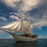 Jakare 35-metre phinisi liveaboard sailing with both masts rigged in Indonesian waters
