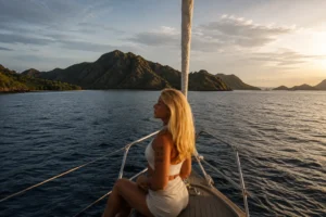 Woman sitting on the deck of a liveaboard boat enjoying the sunset view while sailing from Lombok to Komodo Island.
