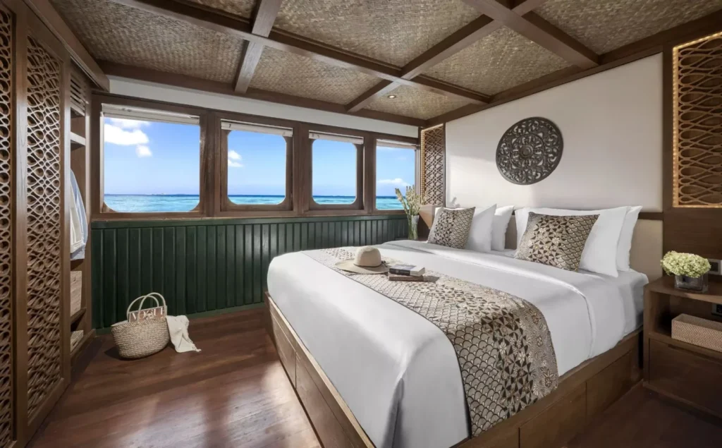 Queen bed and ocean-view windows in the Samsara Samudra Luxury Suite