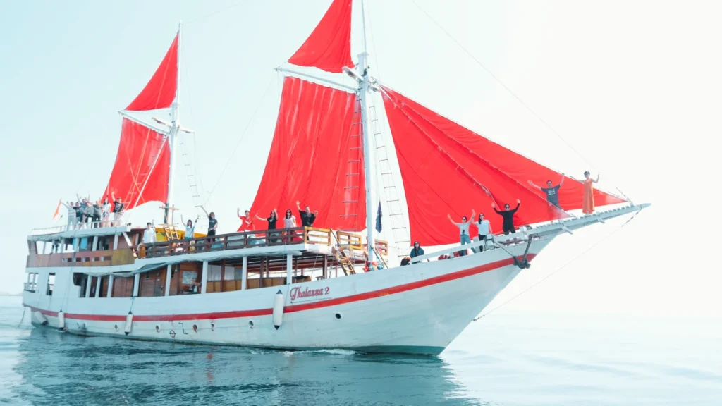 Thalassa 2 phinisi side profile with guests and red sails